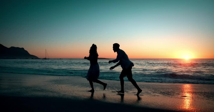 Couple, silhouette and waves at beach with playing for vacation, holiday and sunset date with freedom. Man, woman and running in ocean water for fun, romance and adventure together in Los Angeles