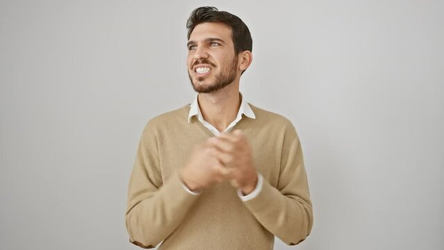 Young hispanic man in sweater, standing frustrated on isolated white background, yelling with aggressive expression, shout mad and crazy, raised arms reeking with stress and anger