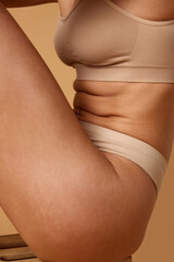Close-up side view of woman's midsection in beige underwear, highlighting skin texture and fit...