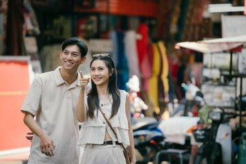 Cheerful young Asian travelers exploring in local market, travel and vacation concept.