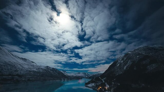 Panoramic timelapse of the moon peaking through clouds and casting reflections in the glacier fjord Holandsfjord in Meløy, Helgeland.