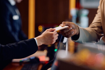Close up of receptions giving cardkey to guest at hotel front desk.