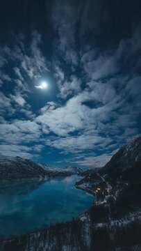 Vertical timelapse of the moon peaking through clouds and casting reflections in the glacier fjord Holandsfjord in Mel&oslash;y, Helgeland.