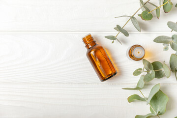 Eucalyptus essential oil in a glass bottle with green eucalyptus leaves on a textured wooden background. Aromatherapy concept. Spa. Natural organic ingredients for cosmetics and body care.Copy space