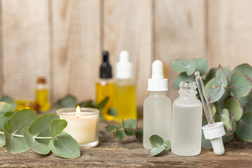 Eucalyptus essential oil in a glass bottle with green eucalyptus leaves on a textured wooden...