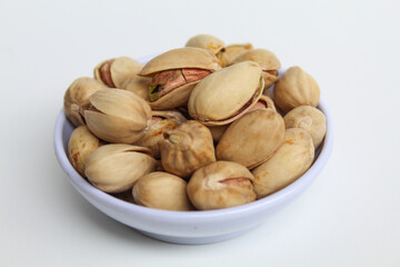 Salted pistachio on the small white bowl, isolated on white background