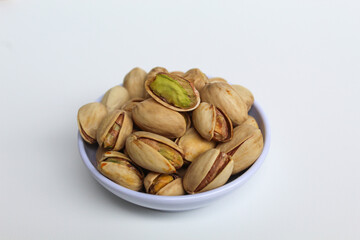 Salted pistachio on the small white bowl, isolated on white background