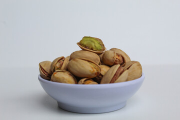 Salted pistachio on the small white bowl, isolated on white background