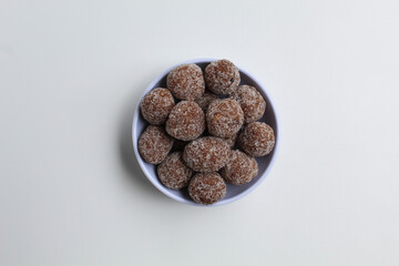 Tamarind candy balls in white bowl. Isolated on white background, flat lay or top view