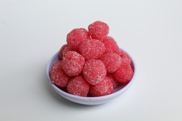 Soursop candy, in pink color and ball shaped, coated by sugar. Isolated on white background