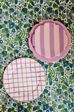 Overhead Shot Of Purple Patterned Ceramic Dishes On Blue And Green Floral Tablecloth, Easter Table Setting