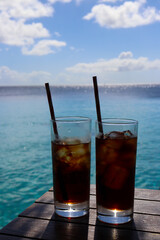 Glasses with iced drinks against turquoise sea water and blue sky in the Caribbean - 752362229