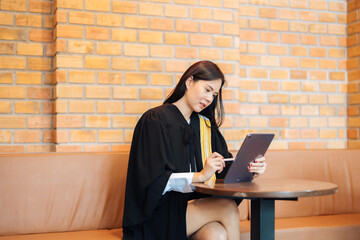 Half body portrait of Asian female lawyer sitting at work desk wearing a legal suit. Look at the...