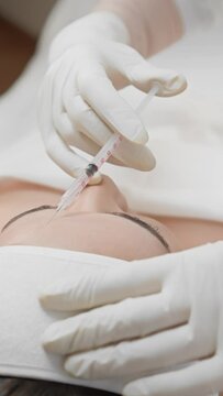 In a beauty salon, a beautician applies Botox injections to a client's face, making her skin look younger and fresher and her facial expressions smooth. During the botulinum toxin therapy procedure