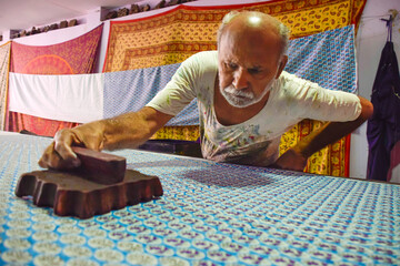 Artisan stamping patterns in ink on traditional Indian textiles as colorful sari