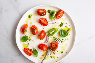 leftover summer salad with tomatoes and pesto on white plate