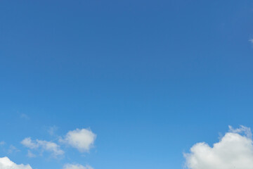 White fluffy clouds in the sky. Blue sky and cloud cover on a sunny summer day. Empty background, copy space