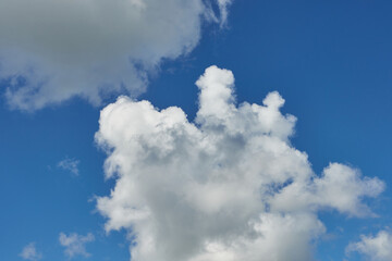 White fluffy clouds in the sky. Blue sky and cloud cover on a sunny summer day. Empty background, copy space