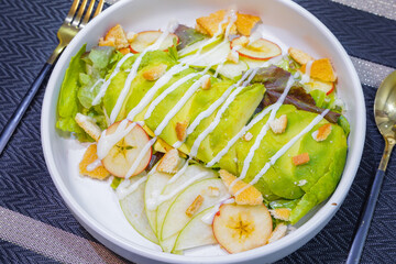 Salad with avocado serving on white plate