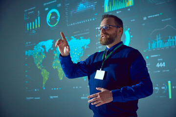 Speaker, lecturer stands near presentation board with graphs, maps and pointing up drawing audience's attention to important details in his speech. Concept of business, startup, personal development.
