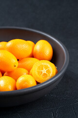 Kumquat fruit in a bowl on a dark background