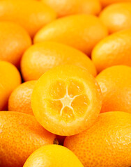 Juicy half of a kumquat on a pile of fruits