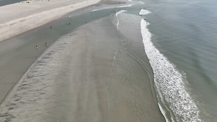Aerial drone view of beach with sand and ocean with waves breaking in the gentle surf during summer in Pawleys Island, South Carolina vacation destination for family 