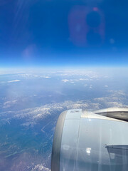 Aerial View of Earth & Bright Blue Sky through the window of an aircraft during flight