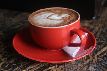 photo of a glass of latte coffee in a red glass with a white tissue