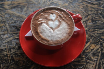photo of a glass of latte coffee in a red glass with a white tissue