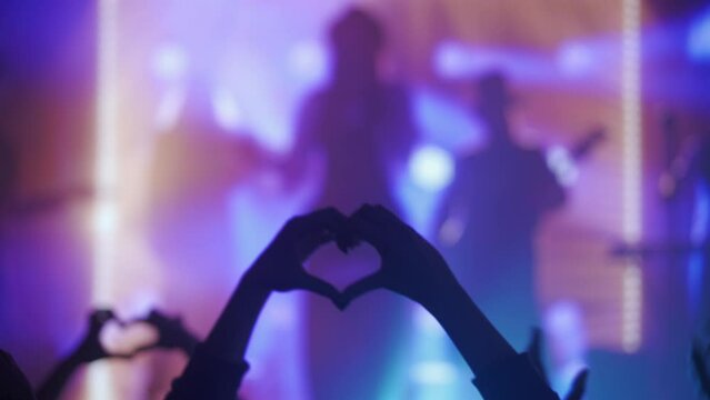 Heart Hands Silhouette at a Concert with Vibrant Stage Lights