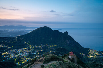 Fototapeta premium At dusk, admire the valley's villages and the sea from the top of the mountain. Teapot Mountain Hiking Trail in Ruifang District, New Taipei City. Taiwan.