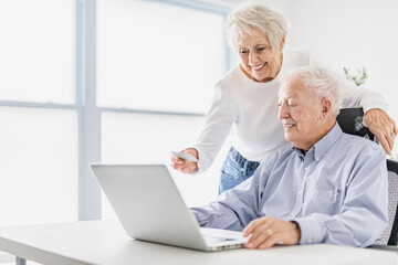 Fototapeta na wymiar senior couple using a laptop while sitting at the office using credit card