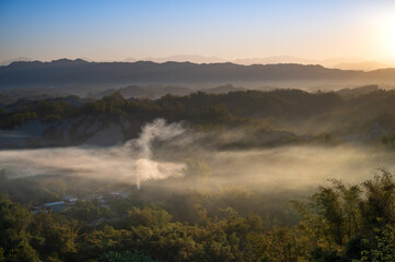 Fototapeta na wymiar In the morning, smoke curls up from the valley and the bamboo forest is green. The Erliao tribe in Zuozhen enjoys the sunrise landscape, Tainan City, Taiwan.