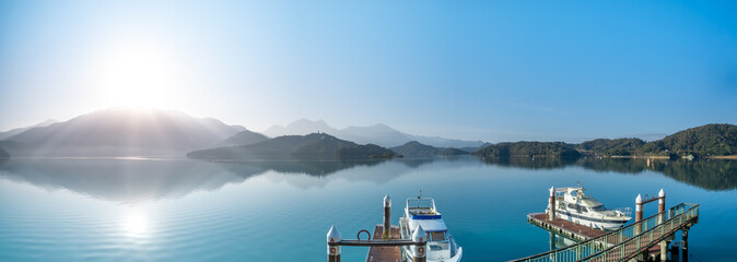 In the early morning sunshine, the dock, lake and mountains are all in sight. Sun Moon Lake is one...