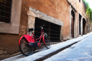 Red antique bicycle along quaint stone Italian street