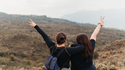 Back view of mother and daughter with arms raised in a victory sign, celebrating on a hike
