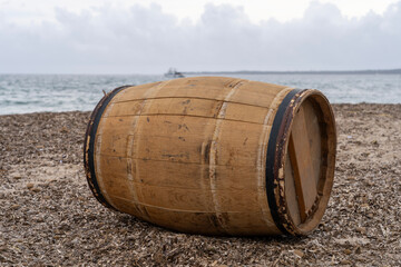 Oak wine barrel on the beach with the sea and clouds in the background. Close-up.