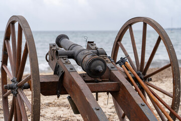 Historical reenactment of events. Cannon from the time of Napoleon Bonaparte on the beach against the backdrop of the sea and clouds. Close-up.