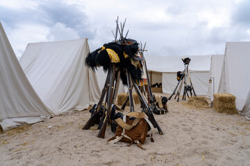 Historical reenactment of events. The reign of Emperor Napoleon I Bonaparte. Rifles with bayonets arranged in a teepee formation, with military headgear placed on top.