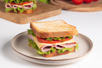 Close-up of two sandwiches with bacon, salami, prosciutto and fresh vegetables on rustic wooden cutting board. Club sandwich concept - 752430817