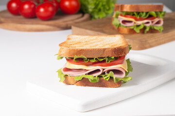 Close-up of two sandwiches with bacon, salami, prosciutto and fresh vegetables on rustic wooden cutting board. Club sandwich concept - 752430843