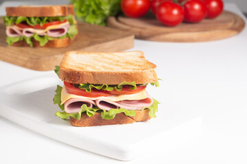 Close-up of two sandwiches with bacon, salami, prosciutto and fresh vegetables on rustic wooden cutting board. Club sandwich concept - 752430857