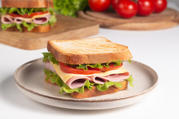 Close-up of two sandwiches with bacon, salami, prosciutto and fresh vegetables on rustic wooden cutting board. Club sandwich concept - 752430870