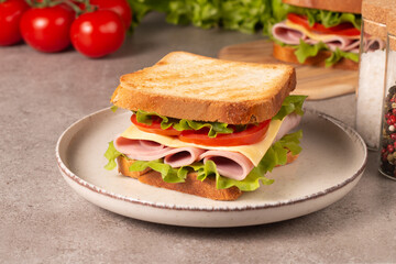 Close-up of two sandwiches with bacon, salami, prosciutto and fresh vegetables on rustic wooden cutting board. Club sandwich concept - 752431031
