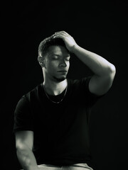 Young man holding his head out of regret or pain. black and white photo