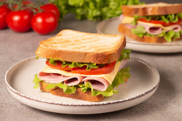 Close-up of two sandwiches with bacon, salami, prosciutto and fresh vegetables on rustic wooden cutting board. Club sandwich concept - 752431215
