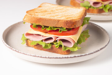 Close-up of two sandwiches with bacon, salami, prosciutto and fresh vegetables on rustic wooden cutting board. Club sandwich concept - 752431254
