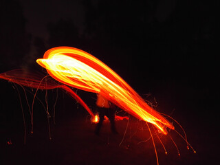 Long exposure abstract photo of a person swinging a burning branch