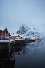Traditional Norwegian fisherman red cabins in the winter morning with fog on the mountain, Lofoten, Nordland of Norway